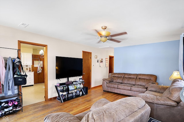 living room featuring a ceiling fan, wood finished floors, visible vents, and baseboards