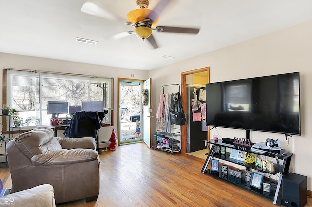 living area featuring wood finished floors, a ceiling fan, visible vents, and a wealth of natural light