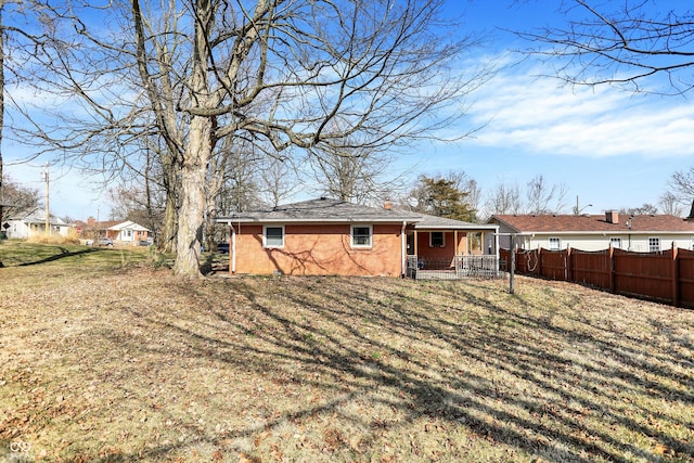 back of house with covered porch, stucco siding, a yard, and fence