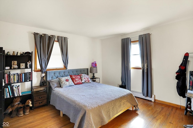 bedroom with wood finished floors, baseboards, and baseboard heating