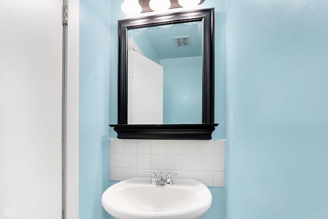 bathroom featuring visible vents, backsplash, and a sink