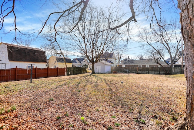 view of yard featuring an outbuilding, a shed, a residential view, and a fenced backyard