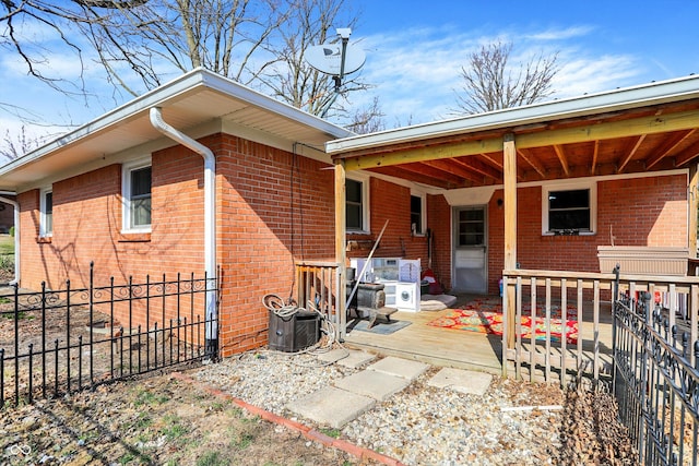 back of house featuring brick siding and fence