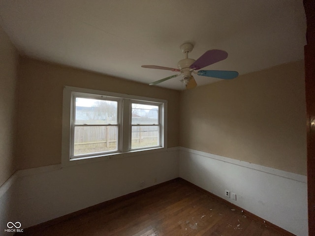 spare room featuring a ceiling fan, dark wood-style flooring, and baseboards