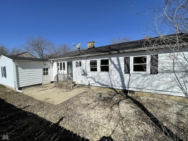 rear view of property with a chimney and a shingled roof