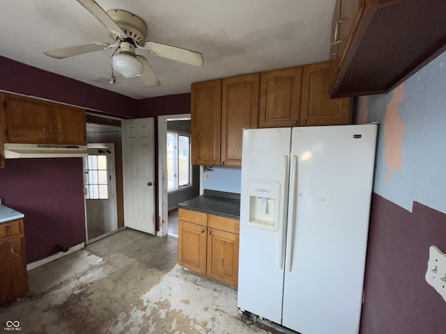 kitchen with a ceiling fan, white refrigerator with ice dispenser, brown cabinetry, and under cabinet range hood