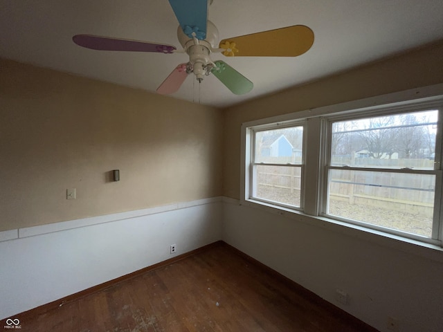 spare room with dark wood finished floors, plenty of natural light, a ceiling fan, and baseboards