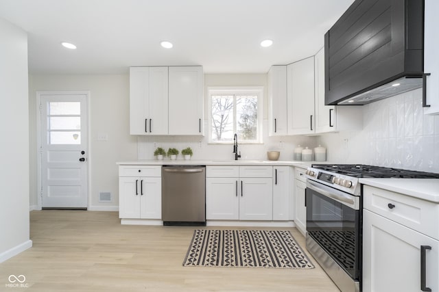 kitchen featuring tasteful backsplash, light countertops, appliances with stainless steel finishes, white cabinetry, and a sink