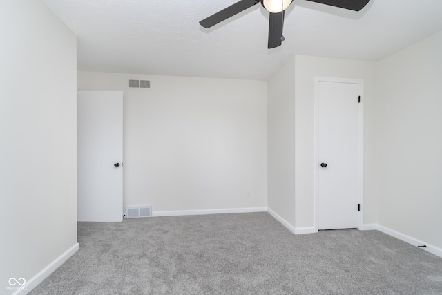 carpeted empty room featuring baseboards, visible vents, and ceiling fan