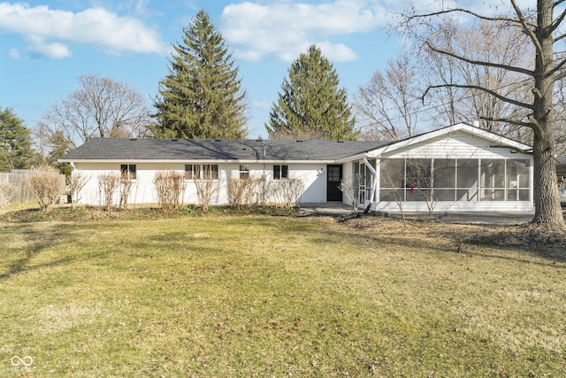 rear view of house with fence, a yard, and a sunroom