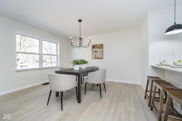 dining area featuring a notable chandelier, light wood-style flooring, visible vents, and baseboards