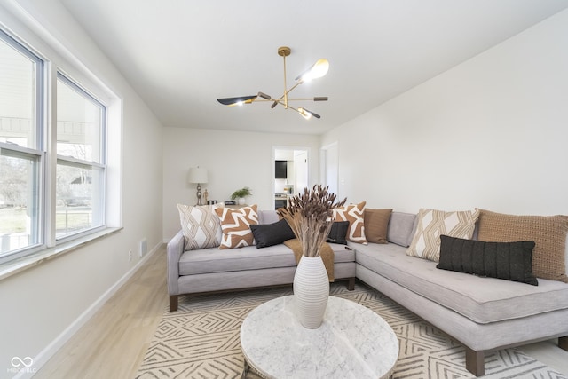 living room featuring visible vents, a notable chandelier, light wood-style floors, and baseboards