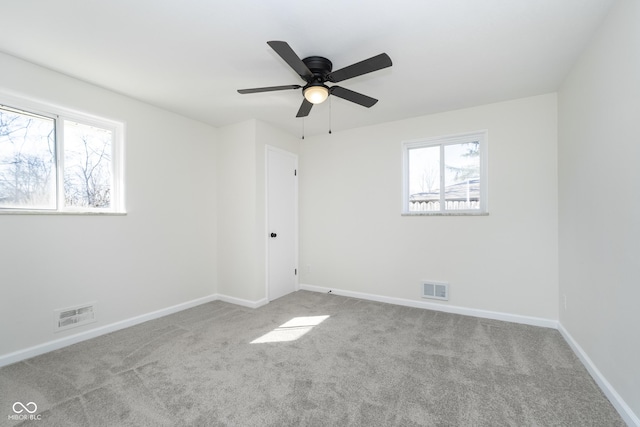 spare room with a ceiling fan, carpet flooring, baseboards, and visible vents