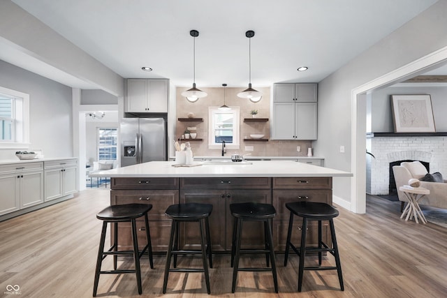 kitchen featuring a breakfast bar, open shelves, stainless steel fridge, and a center island