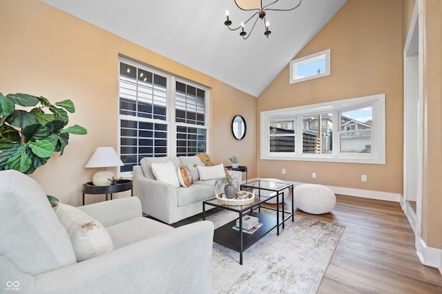 living area featuring a notable chandelier, wood finished floors, baseboards, and high vaulted ceiling