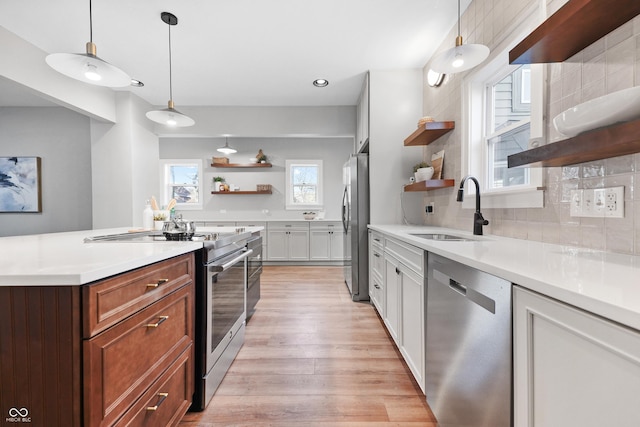 kitchen featuring light wood finished floors, open shelves, a sink, appliances with stainless steel finishes, and backsplash