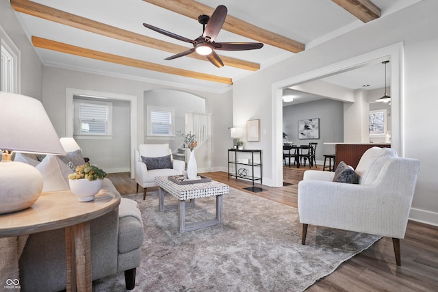 living area with beam ceiling, wood finished floors, baseboards, and ceiling fan