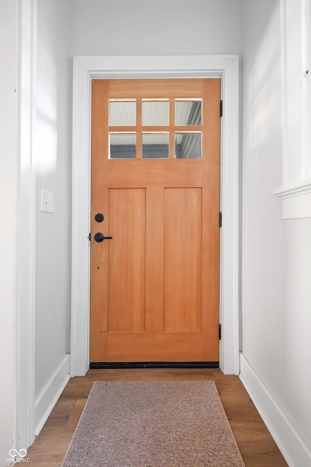 doorway to outside featuring baseboards and wood finished floors