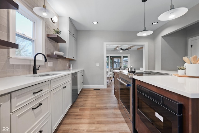 kitchen featuring a sink, decorative backsplash, light wood-style flooring, stainless steel appliances, and open shelves