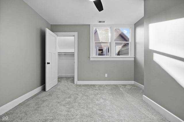 unfurnished bedroom featuring a spacious closet, visible vents, baseboards, and carpet floors