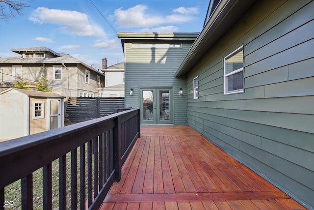 wooden terrace with an outbuilding, a shed, and french doors