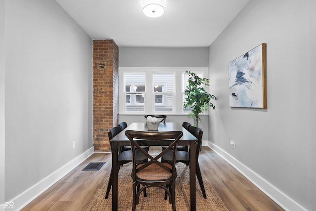 dining area featuring visible vents, baseboards, and wood finished floors