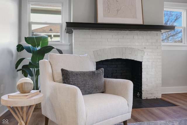 living area with a brick fireplace, wood finished floors, and baseboards