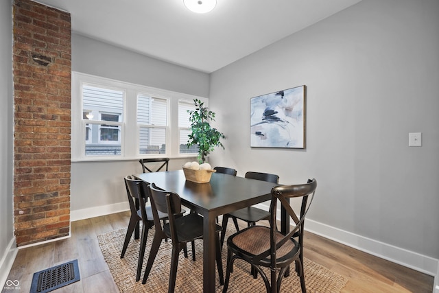 dining area featuring visible vents, baseboards, and wood finished floors