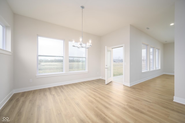 unfurnished dining area with a notable chandelier, baseboards, and light wood-type flooring