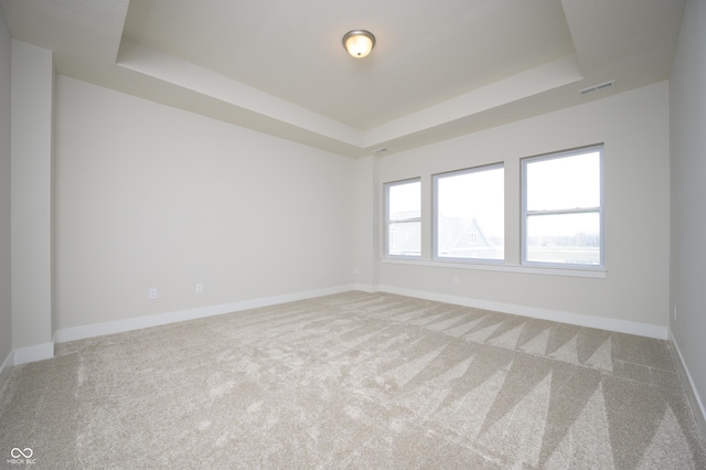 carpeted empty room featuring visible vents, baseboards, and a tray ceiling