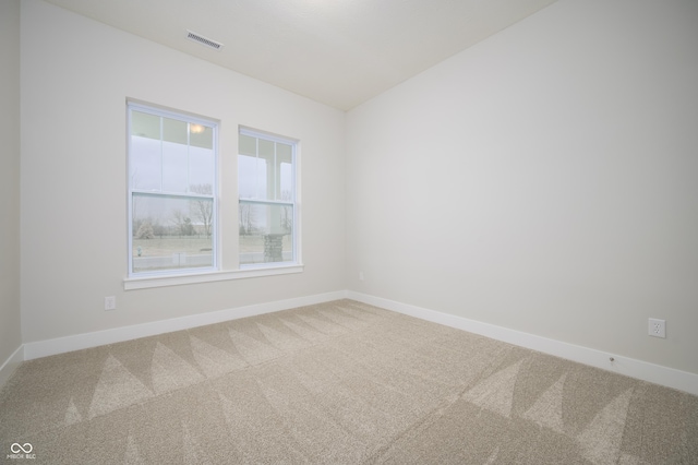 carpeted spare room with visible vents and baseboards