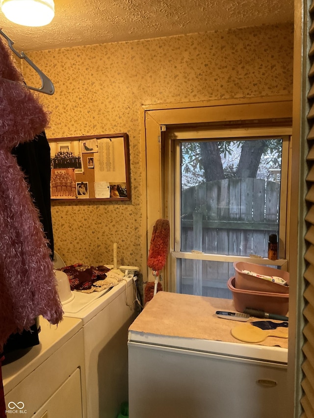 laundry room featuring wallpapered walls, laundry area, a textured ceiling, and washer and clothes dryer