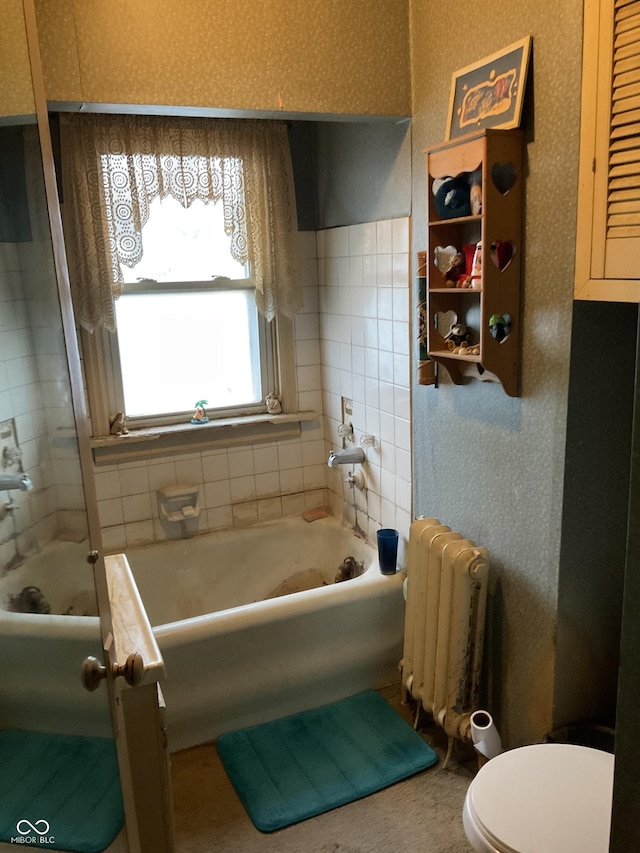 bathroom with wallpapered walls, radiator, and a bathtub