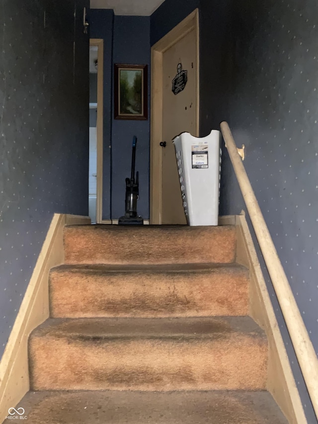 stairs featuring wallpapered walls