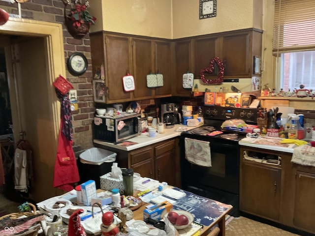 kitchen featuring light countertops, electric range, stainless steel microwave, and brick wall