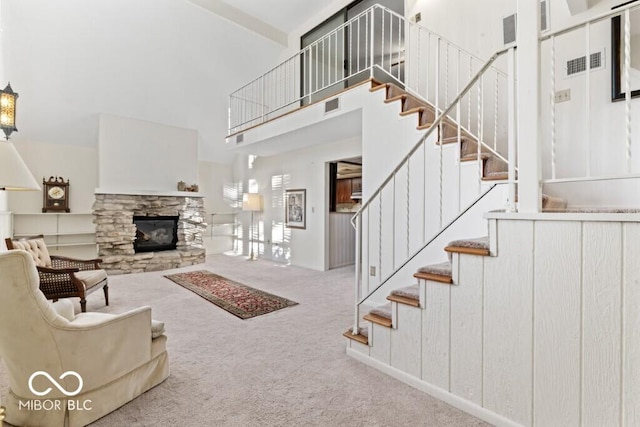 2447 N E Raintree Dr, New Castle, IN 47362 - living area featuring carpet flooring, a towering ceiling, stairs, and a stone fireplace