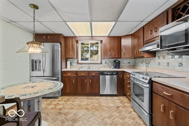 2447 N E Raintree Dr, New Castle, IN 47362 - kitchen with appliances with stainless steel finishes, under cabinet range hood, light countertops, hanging light fixtures, and a drop ceiling
