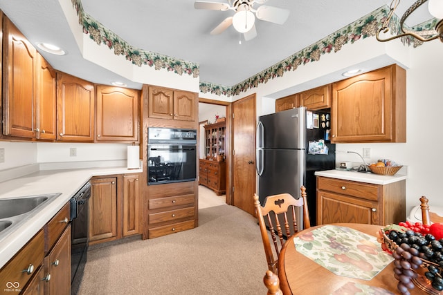 kitchen with brown cabinetry, black appliances, a ceiling fan, and light countertops