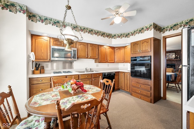 kitchen with brown cabinets, black appliances, a ceiling fan, a sink, and light countertops