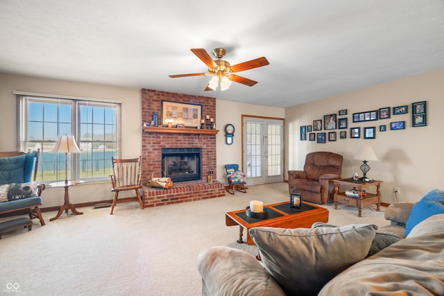 carpeted living room with a brick fireplace, baseboards, and a ceiling fan