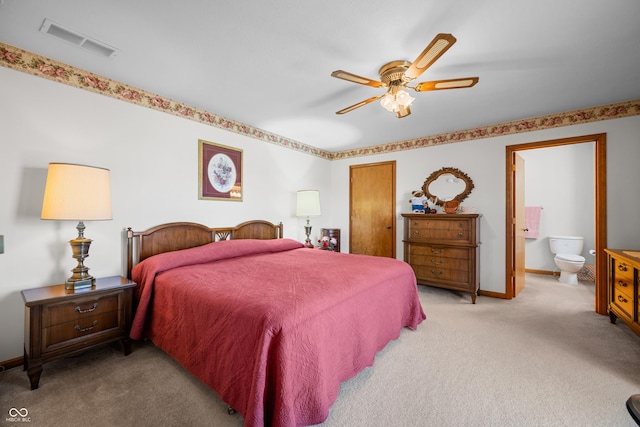 carpeted bedroom with ensuite bath, baseboards, visible vents, and ceiling fan