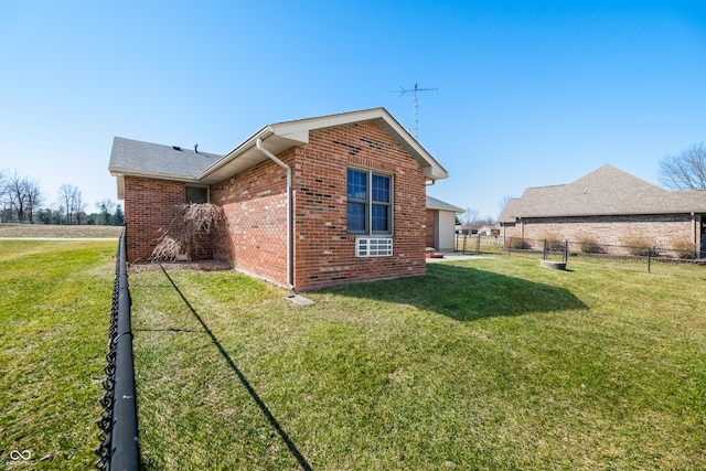 view of property exterior featuring brick siding, a yard, and fence