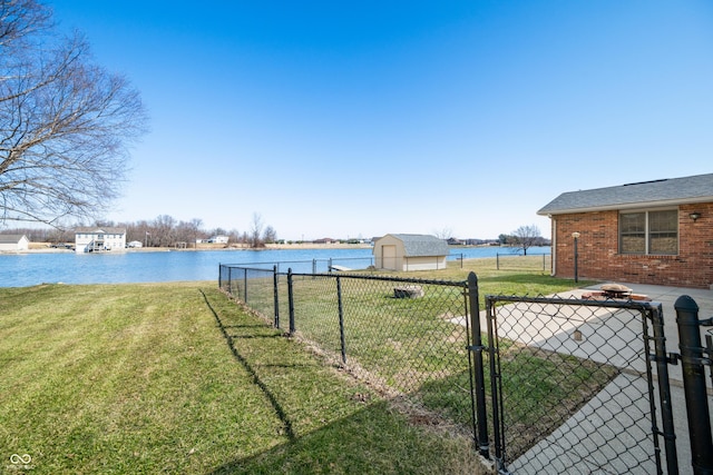 view of yard featuring an outbuilding, a gate, fence, and a water view