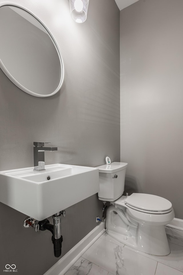 bathroom featuring a sink, baseboards, toilet, and marble finish floor