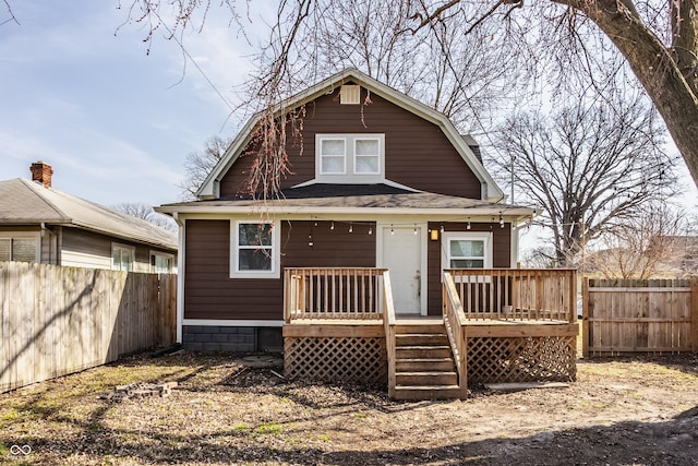 back of house with a deck, a fenced backyard, and a gambrel roof