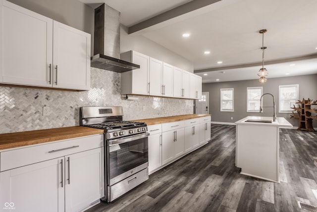 kitchen with butcher block countertops, beamed ceiling, gas stove, wall chimney exhaust hood, and a sink