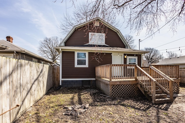 back of property featuring a deck, fence, and a gambrel roof