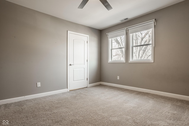 spare room featuring carpet flooring, visible vents, baseboards, and ceiling fan