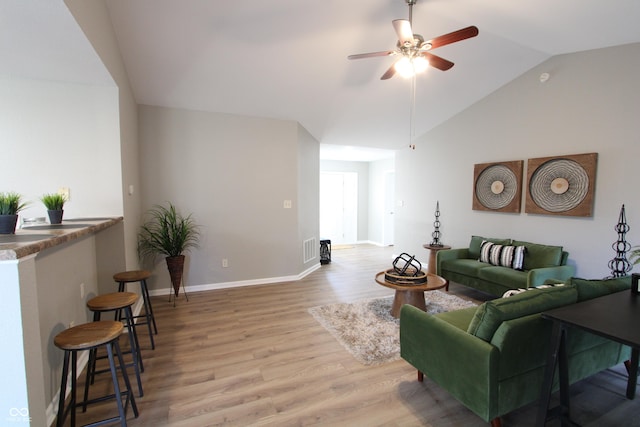 living area featuring visible vents, baseboards, ceiling fan, vaulted ceiling, and wood finished floors