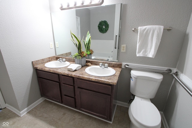 full bathroom with a sink, baseboards, toilet, and double vanity